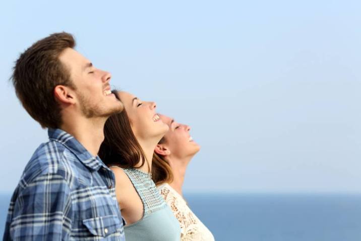 Group of three friends breathing deep fresh air on the beach